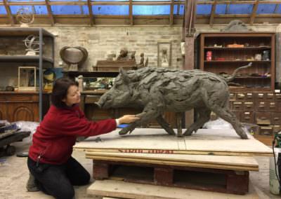 Tanya Russell sculpting a wild boar in her studio using clay