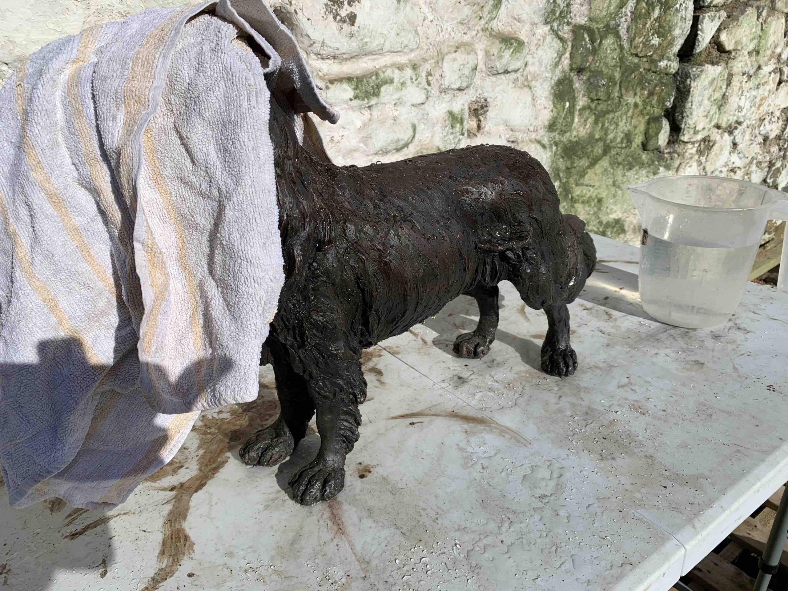 cleaning a bronze sculpture with a towel